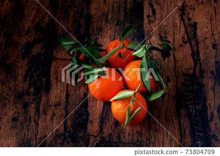 Clementines with leaves in a blue ceramic dish on an old wooden table Clementines with leaves in a blue ceramic dish on an old wooden table 73804709