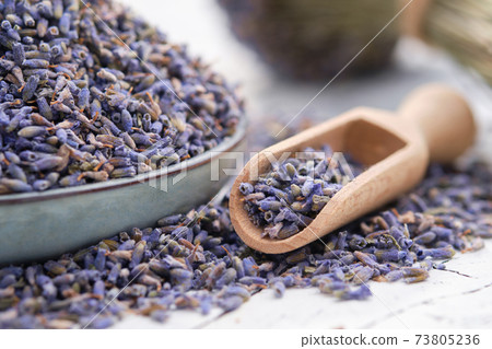 Blue plate of dried lavender. Wooden scoop of dry lavender flowers close up. 73805236