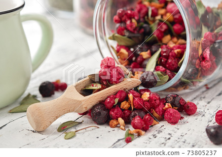 Glass jar of fruit tea with apples, orange, red and black currant berries close up on white kitchen table. Glass jar of fruit tea with apples, orange, red and black currant berries close up on white kitchen table. 73805237