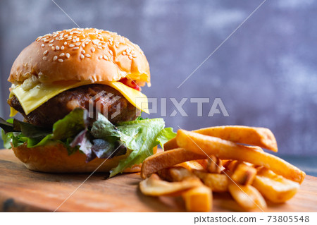 fresh tasty homemade hamburger with fresh vegetables, lettuce, tomato, cheese on a cutting board with French fries. Free space for text 73805548
