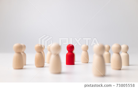 A wooden figure standing with a team to influence and empowerment. Concept of leadership, successful competition winner and Leader with influence and Social distancing for a new normal lifestyle 73805558