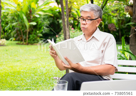 senior old man reading a book in the park and drinking water. Concept of retirement lifestyle and hobby. 73805561