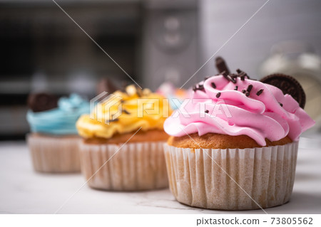 Delicious homemade cupcakes with Colorful cream and topping with candy and Chocolate Cookies. Homemade autumn holiday dessert 73805562