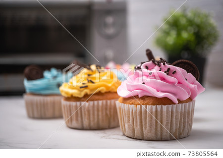 Delicious homemade cupcakes with Colorful cream and topping with candy and Chocolate Cookies. Homemade autumn holiday dessert 73805564