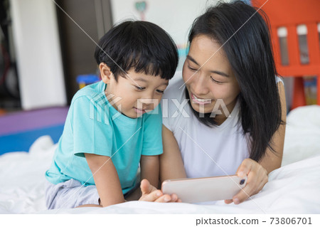 close up of happy mother and her son Taking pictures or selfie or video call or relatives in a bed. Concept of new generation, family, parenthood, authenticity, connection. 73806701