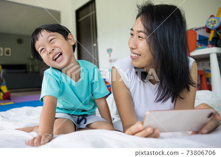 close up of happy mother and her son Taking pictures or selfie or video call or relatives in a bed. Concept of new generation, family, parenthood, authenticity, connection. 73806706