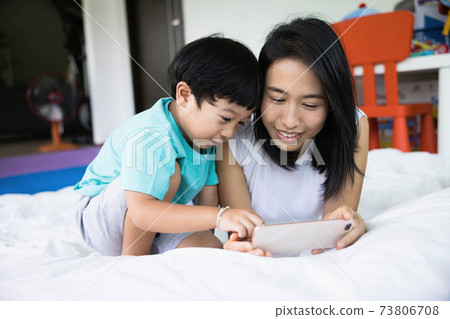 close up of happy mother and her son Taking pictures or selfie or video call or relatives in a bed. Concept of new generation, family, parenthood, authenticity, connection. 73806708