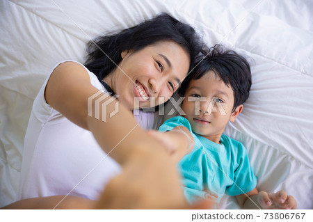 Authentic close up of happy mother and her son in a bed. Concept of new generation, family, parenthood, authenticity, connection. Authentic close up of happy mother and her son in a bed. Concept of new generation, family, parenthood, authenticity, connection. 73806767