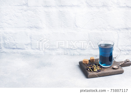 Thai blue tea anchan of buds klitoria Ternate in a glass cup, grey concrete background. Copy space. 73807117