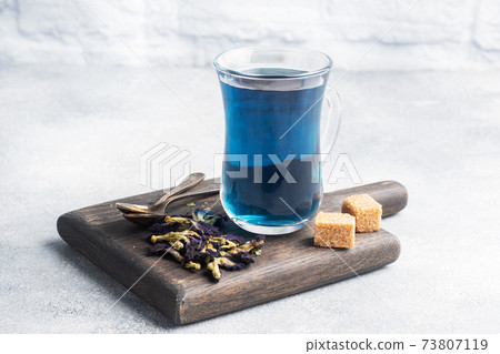 Thai blue tea anchan of buds klitoria Ternate in a glass cup, grey concrete background. Copy space. 73807119