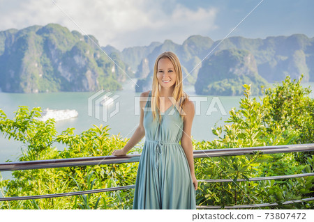 Attractive woman in a dress is traveling in Halong Bay. Vietnam. Travel to Asia, happiness emotion, summer holiday concept. Picturesque sea landscape. Ha Long Bay, Vietnam Attractive woman in a dress is traveling in Halong Bay. Vietnam. Travel to Asia, happiness emotion, summer holiday concept. Picturesque sea landscape. Ha Long Bay, Vietnam 73807472