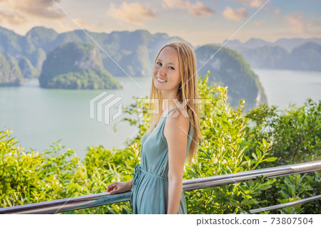 Attractive woman in a dress is traveling in Halong Bay. Vietnam. Travel to Asia, happiness emotion, summer holiday concept. Picturesque sea landscape. Ha Long Bay, Vietnam 73807504