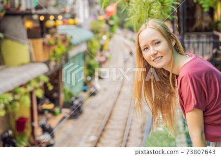 Woman is walking of Hanoi city railway. Perspective view running along narrow street with houses in Vietnam. Hanoi train street, old house and railroad. Vietnam reopens after coronavirus quarantine Woman is walking of Hanoi city railway. Perspective view running along narrow street with houses in Vietnam. Hanoi train street, old house and railroad. Vietnam reopens after coronavirus quarantine 73807643