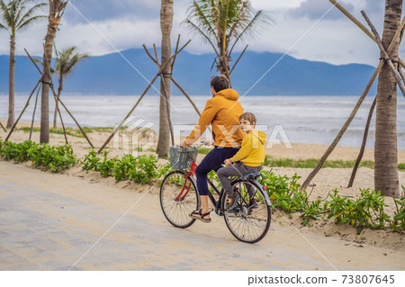 Father with his son having a weekend excursion on bike on a summer day in beautiful landscape 73807645