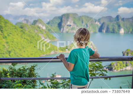 Boy traveler in Halong Bay. Vietnam. Travel to Asia, happiness emotion, summer holiday concept. Picturesque sea landscape. Ha Long Bay, Vietnam. After coronavirus COVID 19 Boy traveler in Halong Bay. Vietnam. Travel to Asia, happiness emotion, summer holiday concept. Picturesque sea landscape. Ha Long Bay, Vietnam. After coronavirus COVID 19 73807649