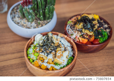 Raw Organic Poke Bowl with Rice and Veggies close-up on the table. Top view from above horizontal 73807654