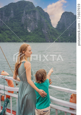 Mom and son travelers is traveling by boat in Halong Bay. Vietnam. Travel to Asia, happiness emotion, summer holiday concept. Traveling with children concept. After COVID 19. Picturesque sea landscape 73807659