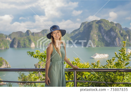 Attractive woman in a dress is traveling in Halong Bay. Vietnam. Travel to Asia, happiness emotion, summer holiday concept. Picturesque sea landscape. Ha Long Bay, Vietnam 73807835