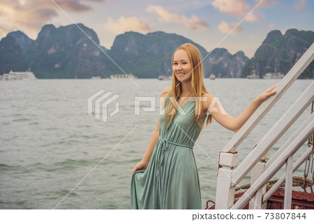 Attractive woman in a dress is traveling by boat in Halong Bay. Vietnam. Travel to Asia, happiness emotion, summer holiday concept. Picturesque sea landscape. Ha Long Bay, Vietnam 73807844