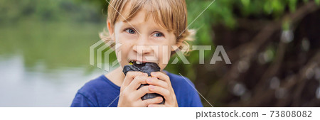 Boy eating Vietnamese Pork Banh Mi Sandwich in a black baguette BANNER, LONG FORMAT 73808082