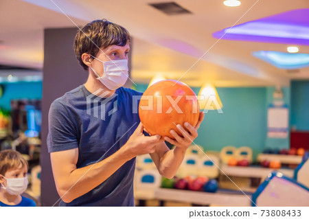 Man playing bowling with medical masks during COVID-19 coronavirus in bowling club Man playing bowling with medical masks during COVID-19 coronavirus in bowling club 73808433