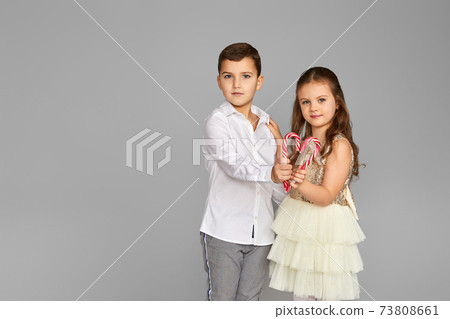 little girl and boy holding two red candy canes in the shape of a heart little girl and boy holding two red candy canes in the shape of a heart 73808661
