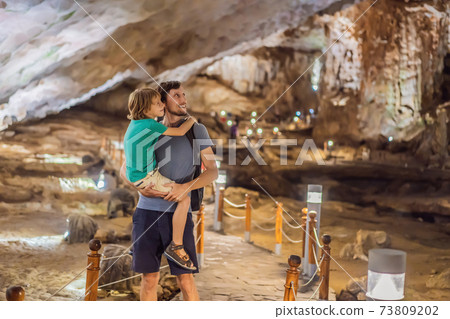 Dad and son tourists in Hang Sung Sot Grotto Cave of Surprises, Halong Bay, Vietnam. Traveling with children concept. Tourism after coronavirus 73809202