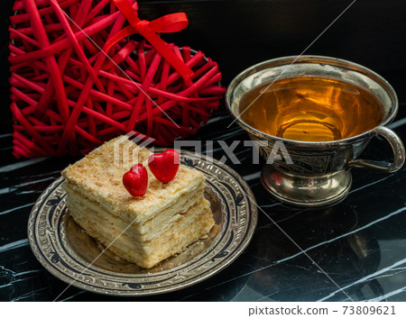 Puff pastry, cup of tea and heart on black marble table Puff pastry, cup of tea and heart on black marble table 73809621