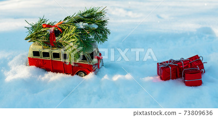 Red toy bus with a Christmas tree on the snow Red toy bus with a Christmas tree on the snow 73809636