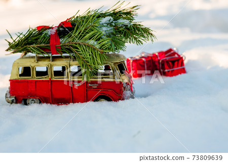 Red toy bus with a Christmas tree on the snow Red toy bus with a Christmas tree on the snow 73809639