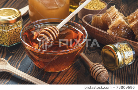 Honey in glass jar with honey dipper over wooden background 73809696