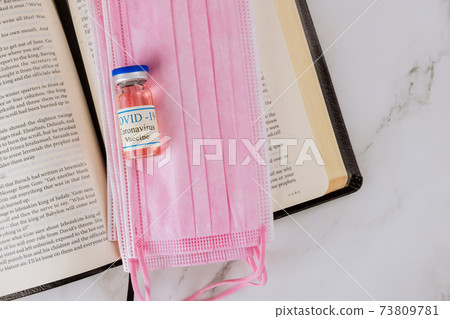 Opened the Holy Bible closeup prayer time with Negative attitude of the church to vaccination and covid-19 vaccine bottle Opened the Holy Bible closeup prayer time with Negative attitude of the church to vaccination and covid-19 vaccine bottle 73809781