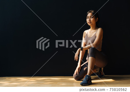 Serious ethnic female athlete preparing for training in studio Serious ethnic female athlete preparing for training in studio 73810562