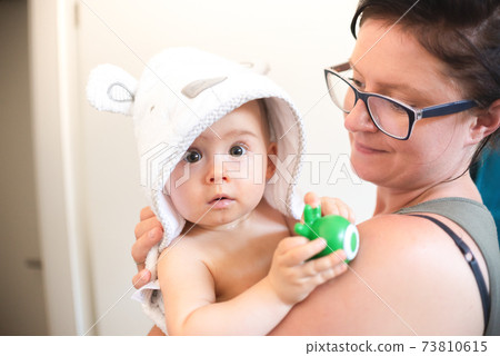 Mother holding baby with bathrobe after eavning bath. 73810615