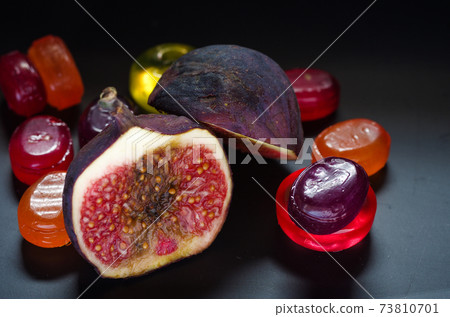 Sweet, ripe figs on a background of colorful candy. Multicolored background, screensaver. Sweet, ripe figs on a background of colorful candy. Multicolored background, screensaver. 73810701