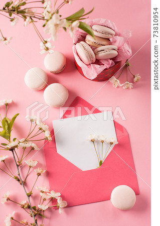 Rose macaroons in gift box, Cherry blossoms, empty envelope. Sweet macarons present on pink background. 73810954