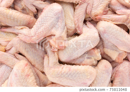 Raw chicken wings close-up. A bunch of chicken wings scattered over the surface. 73811048