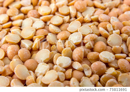 A pile of chopped peas scattered on the surface. Dry peas of yellow color close-up. A pile of chopped peas scattered on the surface. Dry peas of yellow color close-up. 73811691