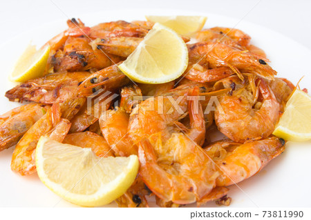Fried prawns on a white plate. Shrimp fried in oil with garlic and lemon on a plate. Fried prawns on a white plate. Shrimp fried in oil with garlic and lemon on a plate. 73811990