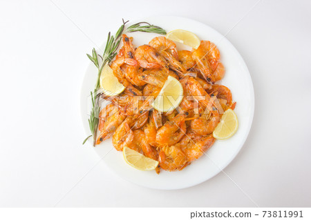 Fried prawns on a white plate. Shrimp fried in oil with garlic and lemon on a plate. Fried prawns on a white plate. Shrimp fried in oil with garlic and lemon on a plate. 73811991