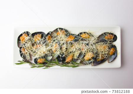 Fried mussels in the sink on a plate. Mussels in a sauce and grated Parmesan on a white background. Fried mussels in the sink on a plate. Mussels in a sauce and grated Parmesan on a white background. 73812188