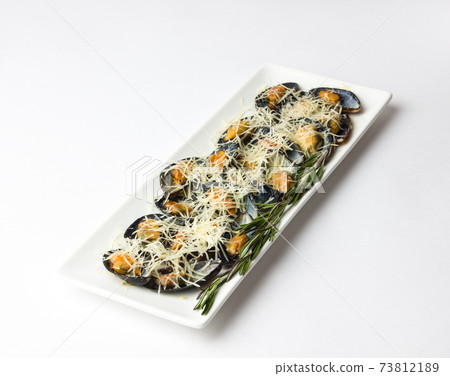 Fried mussels in the sink on a plate. Mussels in a sauce and grated Parmesan on a white background. 73812189