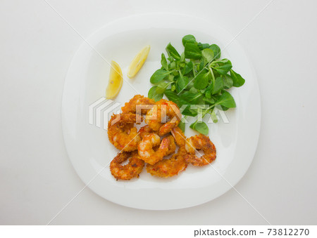 Fried shrimps on a plate. Prawns fried in breading on a white plate with salad and lemon. Fried shrimps on a plate. Prawns fried in breading on a white plate with salad and lemon. 73812270