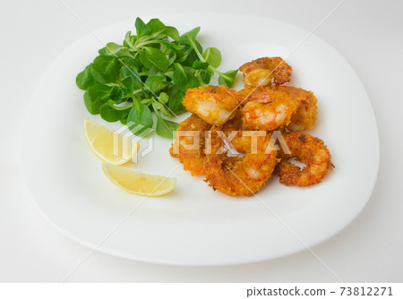 Fried shrimps on a plate. Prawns fried in breading on a white plate with salad and lemon. Fried shrimps on a plate. Prawns fried in breading on a white plate with salad and lemon. 73812271