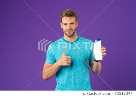 Man show thumbs up with shampoo bottle on violet 73812344