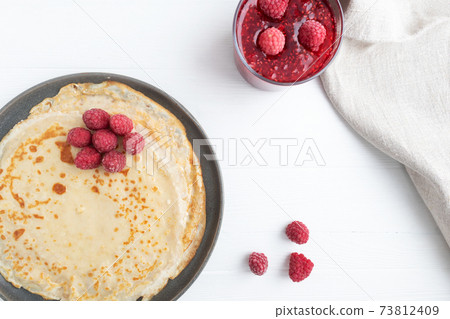Pancakes in a plate and jam on a white wooden background with space for text. Pancake week. 73812409