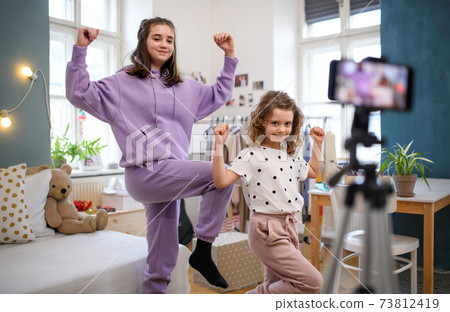 Sisters indoors at home, making video with smartphone. Lockdown concept. 73812419