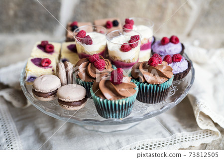 Selection of colorful and delicious cake desserts on tray on table. 73812505