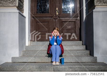 Tired woman caregiver or healthcare worker having a break outdoors, coronavirus concept. 73812541