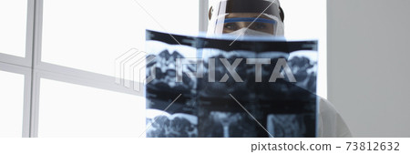 Doctor in protective suit holding x-ray picture in clinic 73812632